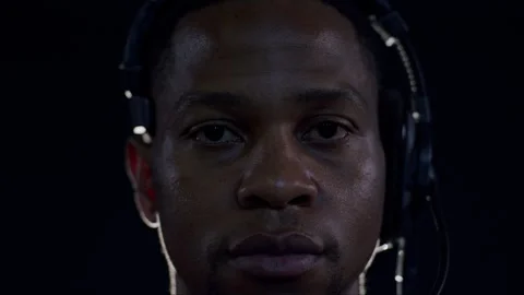 Close-up of a focused stage technician adjusting headset under dramatic lighting Stock Footage 296577602