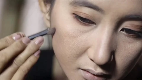 Close-up of a focused woman applying face makeup with precision Stock Footage 313165104