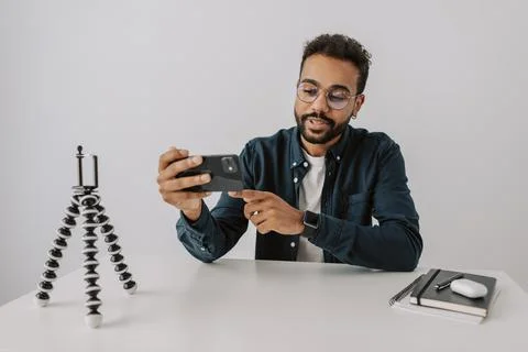 Close up focused young smart black blogger man record vlog with phone on tripod Stock Photos