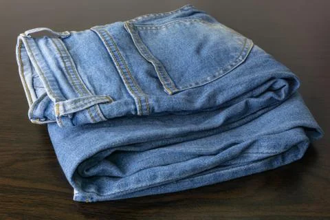 Close up of folded casual cool blue jeans on the wooden table. 스톡 사진
