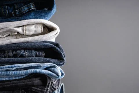 Close up of folded jeans on gray background with space for text. Stock Photos