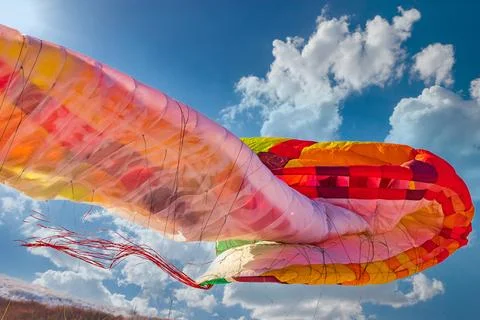 Close-up on the folding multi-colored wing of a paraglider during landing Stock Photos