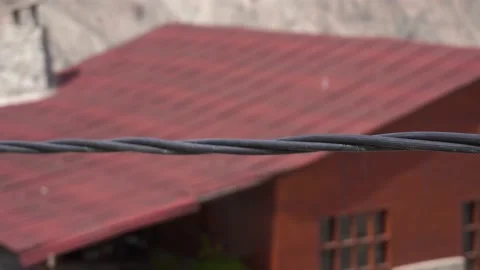 Close-up following a black power cable hanging between a beautiful landscape bet Video stock 199477733