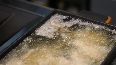 Close-up of Food Deep Frying in Hot Bubbling Oil in a Professional Kitchen Fryer Stock Footage 337440587