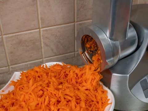 Close-up of a food processor grating red carrots. Processing of ripe fresh Stock Photos