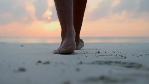 Close-up of the foot of a men walking barefoot along the shore of a sandy beach Stock Footage 242468329