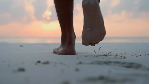 Close-up of the foot of a men walking barefoot along the shore of a sandy beach Stock Footage 242559313