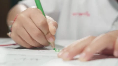 Close-up footage of a child's hand using a green colored pencil to color a .. Stock Footage 342216628