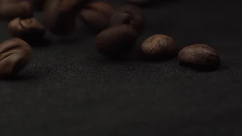 Close up footage of coffee beans falling on black table spinning around. Macro Stock Footage 127003643