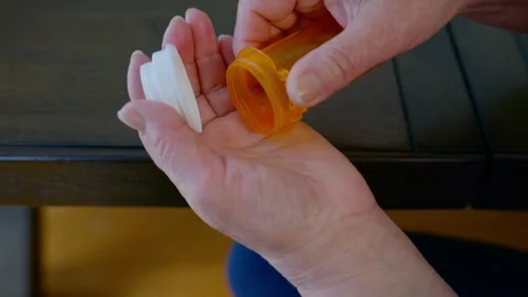 Close up footage of elderly hands pouring pills from an orange prescription Stock Footage 331033745