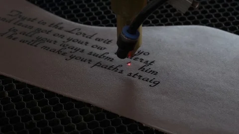 Close-up footage of laser machine engraving holy bible quote on leather sheet Stock Footage 125478128