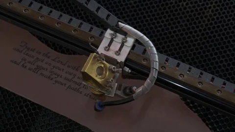 Close-up footage of laser machine engraving holy bible quote on leather sheet Stock Footage 125478244