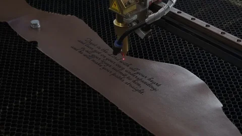 Close-up footage of laser machine engraving holy bible quote on leather sheet Stock Footage 125478268