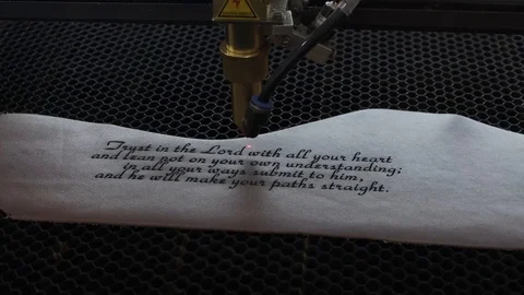 Close-up footage of laser machine engraving holy bible quote on leather sheet Stock Footage 125478295