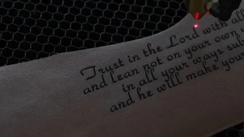 Close-up footage of laser machine engraving holy bible quote on leather sheet Stock Footage 125478308