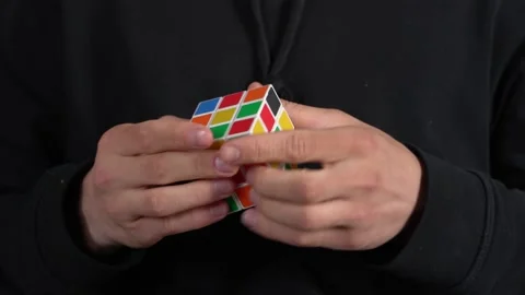 Close up footage of a man's hands solving a Rubik's cube puzzle, isolated on a Stock Footage 185123938