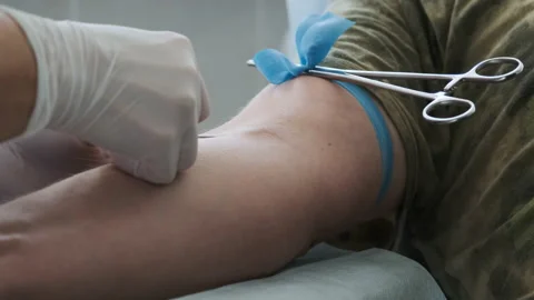 Close up footage nurse insert needle into man vein in order for the person to Stock-Footage 139073772