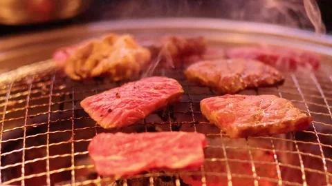 Close up footage of raw beef slices grilling over hot coals on a metal grat.. Vídeos de archivo 333697217