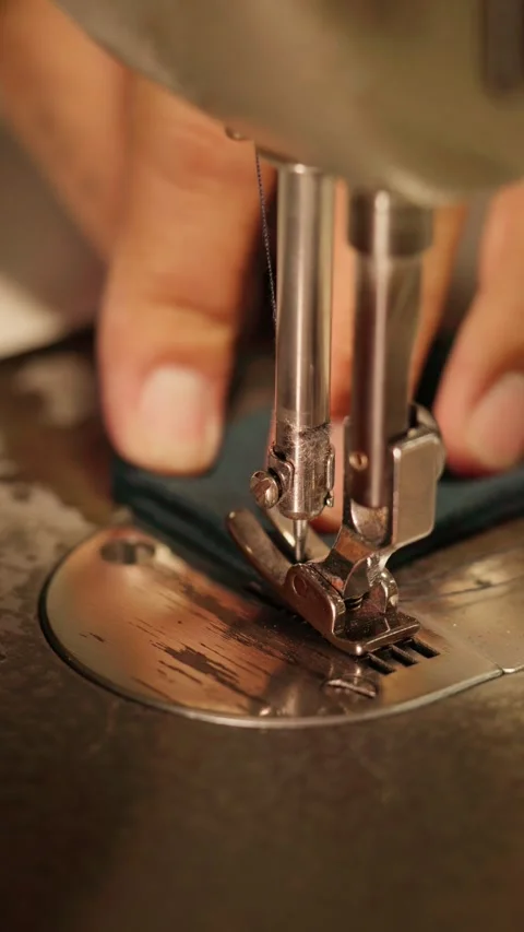 Close-up footage showing hands positioning dark blue fabric under a sewing .. Stock Footage 342492138