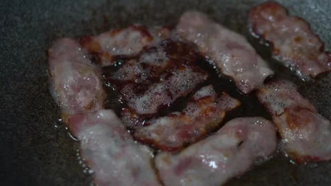 Close up footage of a slice of tasty bacon fried with oil in a cast-iron pan. 스톡 동영상 334643270