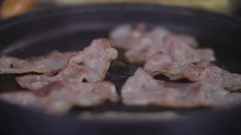Close up footage of a slice of tasty bacon fried with oil in a cast-iron pan. 스톡 동영상 334643287