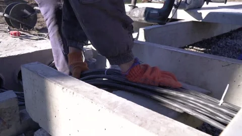 Close up footage of a worker laying cable in a concrete chute, construction Stock Footage 160114650