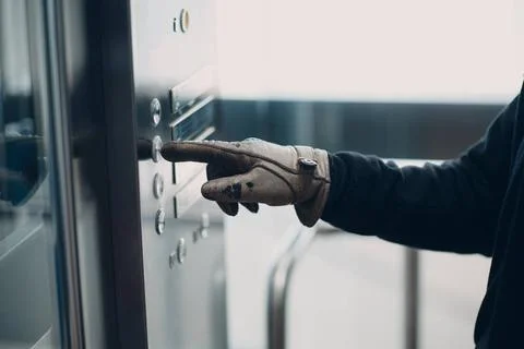 Close up of forefinger in glove pressing the button elevator during corona... Foto stock