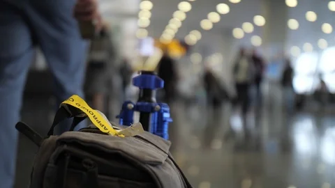 Close-up. In the foreground is a bag, a man picks it up and walks away. Airport Stock Footage 107825405