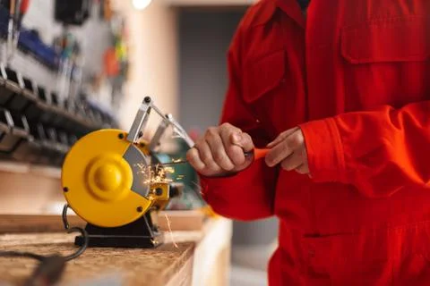 Close up foreman in orange work clothes using knife sharpener in Foto stock