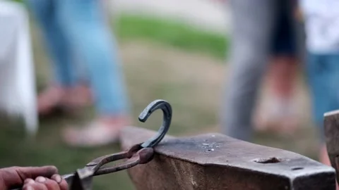 Close-up of forging a horseshoe. The blacksmith teaches the apprentice to knock Stock Footage 162305491