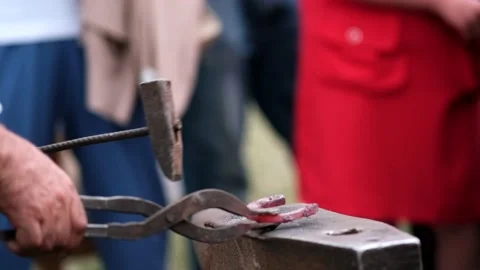 Close-up of forging a horseshoe. The blacksmith teaches the apprentice Stock Footage 164896376