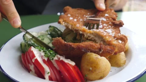 Close up of fork and knife cutting piece of vegan steak served with vegetables Stock Footage 138792632