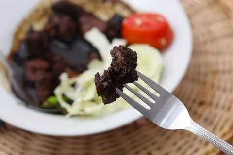 Close-up of a fork with cooked beef and vegetables on plate Stock Photos