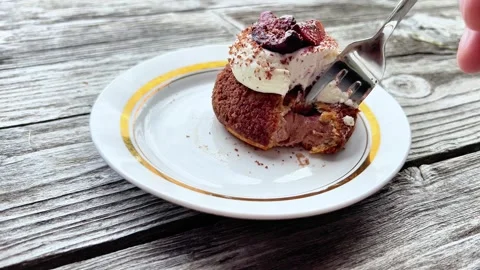 Close-Up of Fork Cutting into Cream-Topped Choux Pastry on Wooden Table Stock Footage 345640255