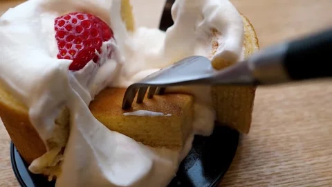 Close-up of a fork cutting into a delicious slice of strawberry shortcake with w Stock Footage 331775660