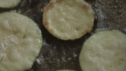 Close-up, fork flipping zucchini sliced into rings frying in oil in pan 库存影片 337112917