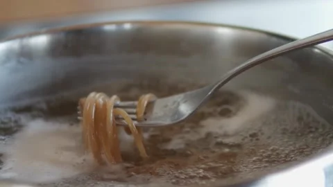 Close-up of a fork lifting some spaghetti as they cook. Stock Footage 155833214