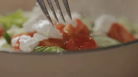 Close up of fork mixing fresh salad ingredients including olives tomatoes feta Stock Footage 344867811