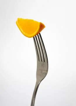 Close up of a fork with a orange on a light gray background. Foto stock