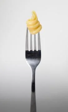 Close up of a fork with pasta on a light gray background. Stock Photos