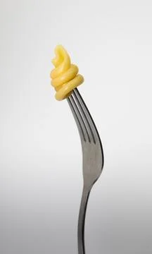 Close up of a fork with pasta on a light gray background. Stock Photos
