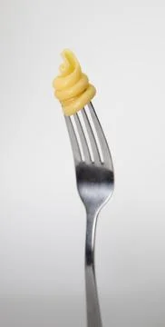 Close up of a fork with pasta on a light gray background. Stock Photos