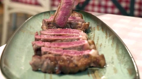 Close up of a fork picking a slice of juicy medium rare steak from a plate Stock Footage 340040467