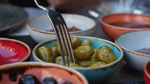 A close-up of a fork takes a green olive from the bowl Stock Footage 223531794