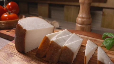 Close-up of a fork taking a piece of semi-hard cheese from the wooden board Stock Footage 148873726