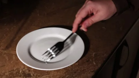 Close-up of a fork tapping on a white plate on a marble countertop Stock Footage 339178816