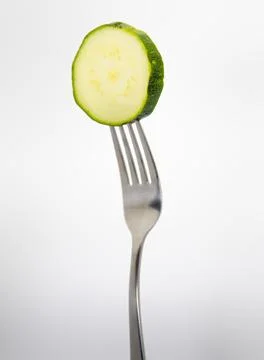Close up of a fork with a zucchini on a light gray background. Foto stock