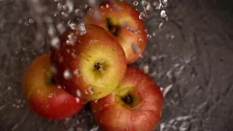 A close up of four apples under running water in slow motion. Stockbeeldmateriaal 305552783
