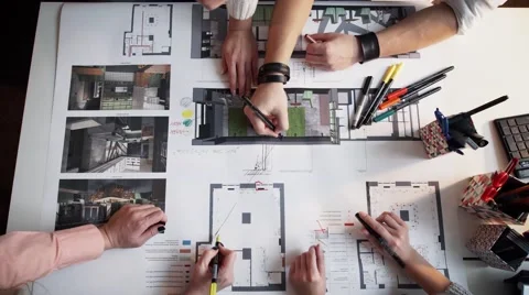 Close Up Of four Architects Discussing Plan Together At Desk With Blueprints Stock Footage