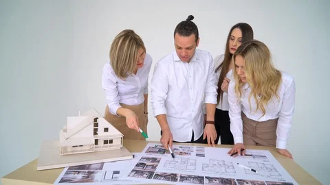 Close Up Of four Architects Discussing Plan Together At Desk With Blueprints Stock Footage 88590767